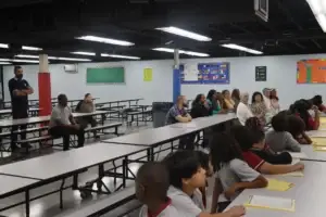 Staff members and students listen during an assembly session in the cafeteria.