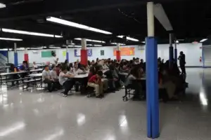 A student stands to respond while a staff member addresses the assembly.