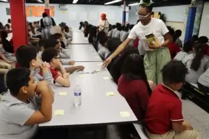 A staff member distributes markers for a student sticky-note reflection activity.