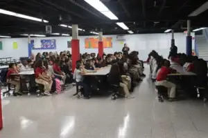 Grades 4–7 students listen to staff members during the assembly in the cafeteria.