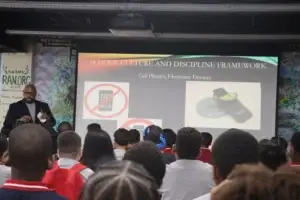 A staff member explains cell phone and electronic device expectations to students.