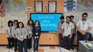 A group of EntreX students in school uniforms stands on both sides of a classroom screen that reads “EntreX Lab — Thank You! Goodwill of Delaware and Delaware County.”